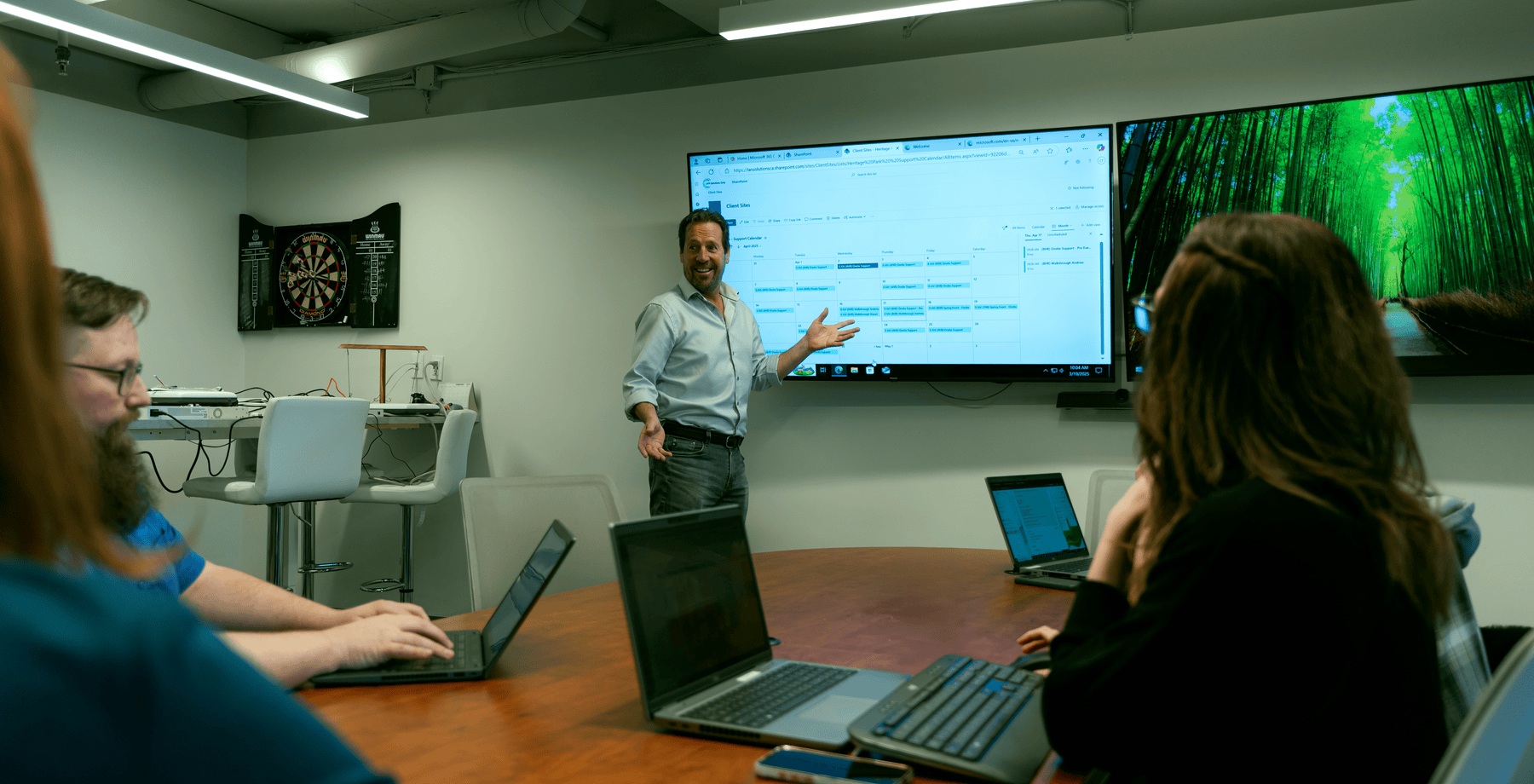 Man presenting on screen in boardroom with colleagues, reflecting LAN Solutions’ people-first IT focus
