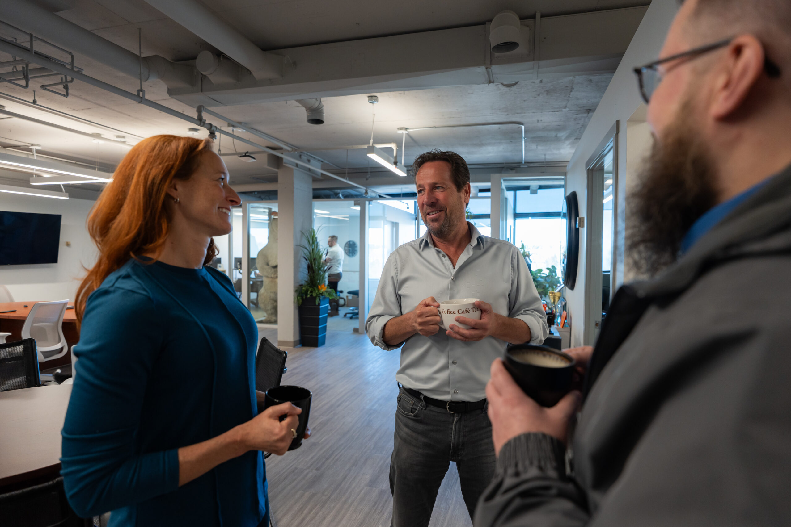 Three business professionals in discussion in an office, collaborating on cybersecurity and insurance strategies